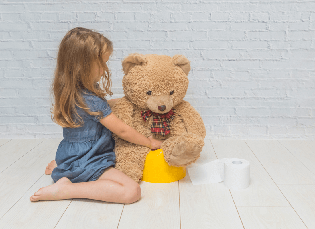 Girl putting teddy on potty