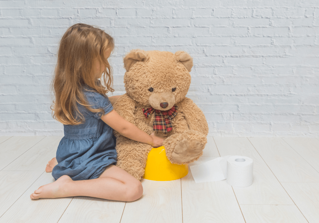 Girl putting teddy on potty