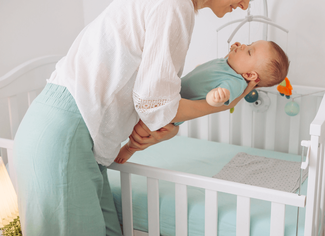 Mum putting baby in cot