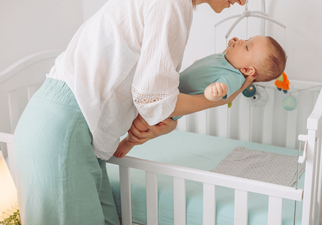 Mum putting baby in cot