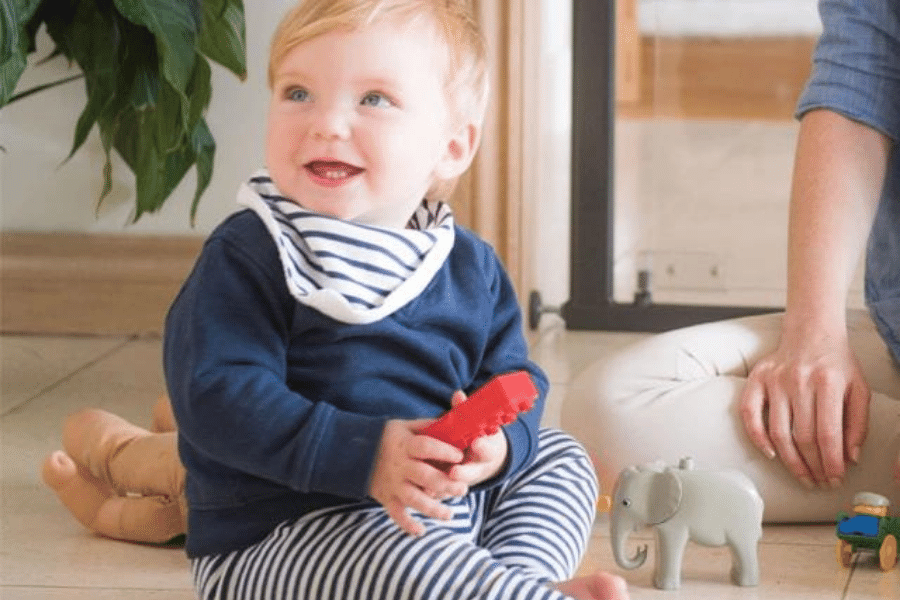 Baby smiling while holding a lego brick